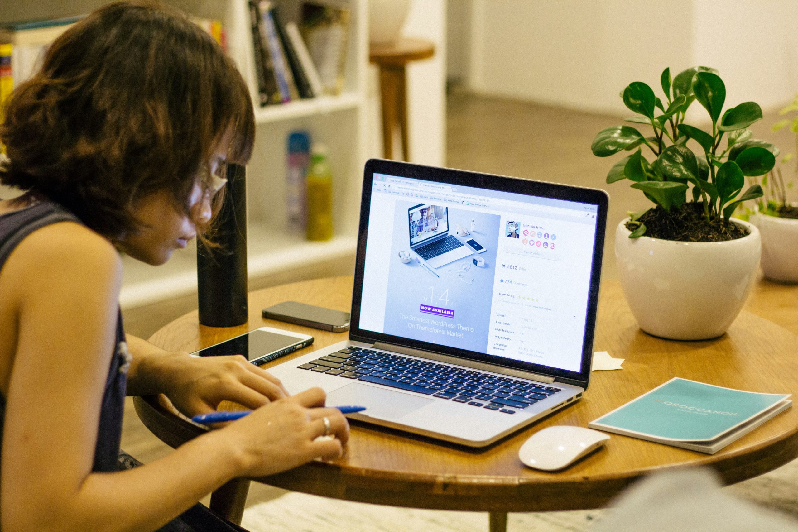 Woman sitting at table browsing a website on laptop